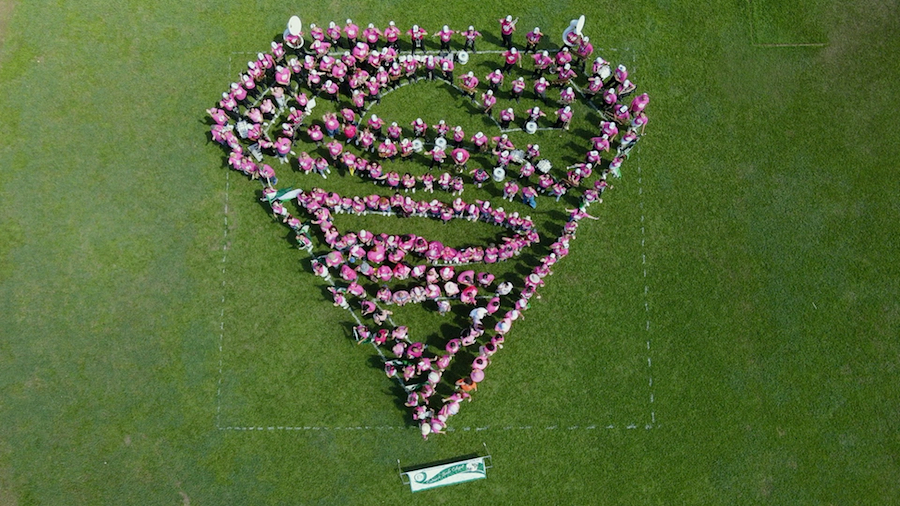 Foto aérea de participantes en la Marcha Rosada del RUM formando la figura de emblema de Súper Chica.