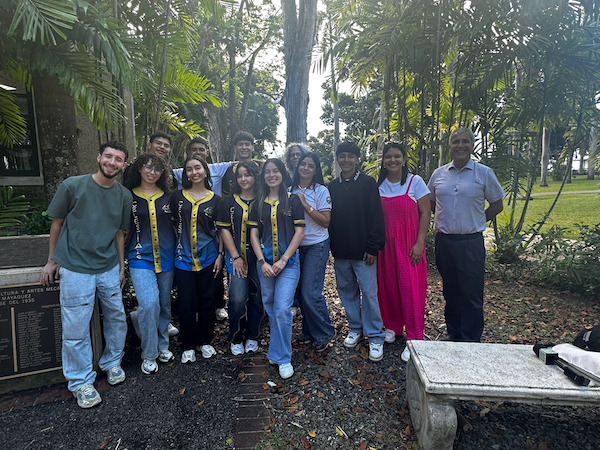 Grupo de estudiantes de la Escuela Superior Josefina León Zayas en Jayuya en su visita al RUM, acompañados de su maestra, consejera y el doctor William Hernández, ayudante especial del Rector (a la extrema derecha), todos de pie en el área del patio del Edificio De Diego.